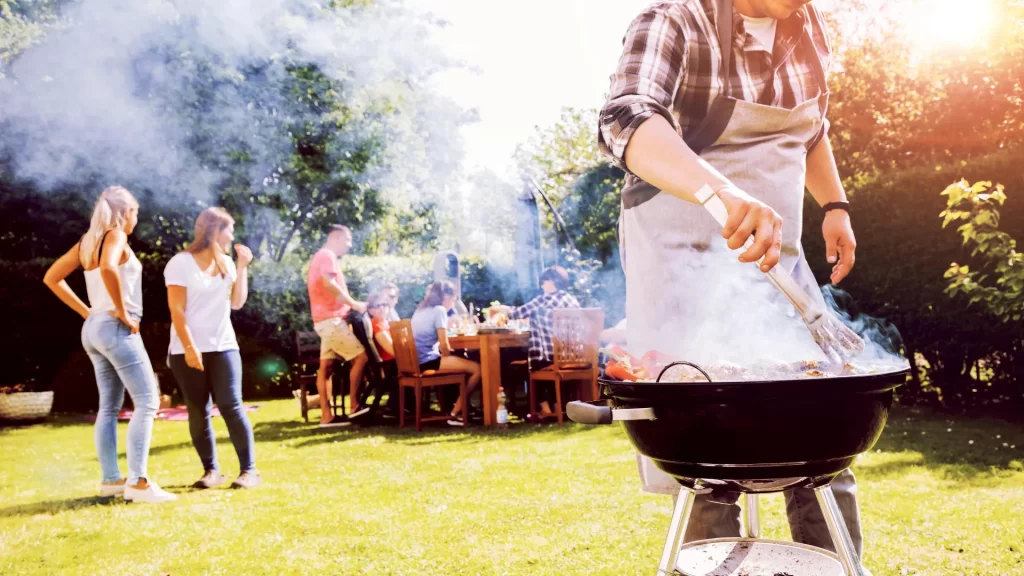 Summer garden bbq party with grill and happy people in dry backyard after a recent french drain installation