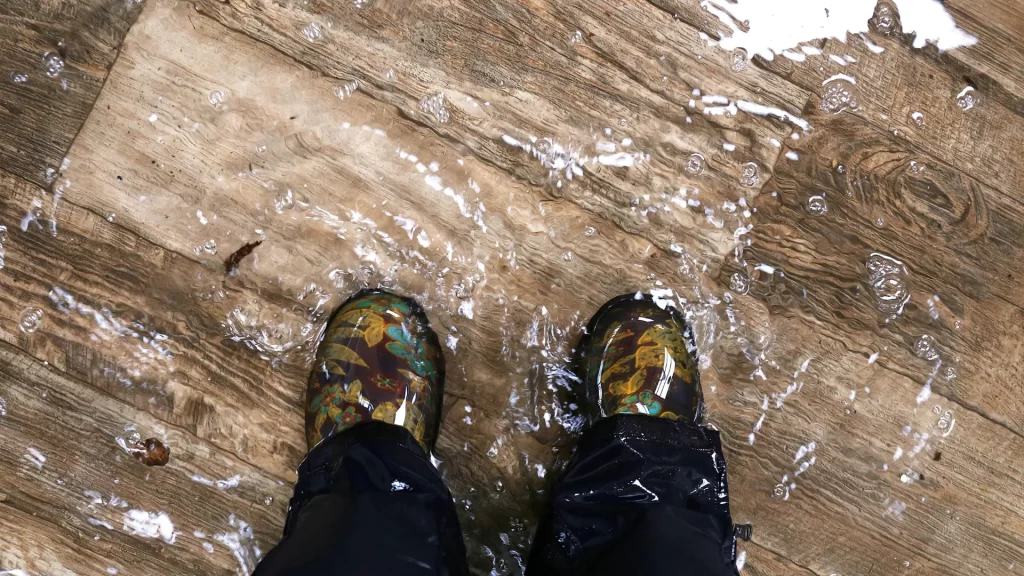 waterproof rain boots standing in a flooded house with vinyl wood floors water damage